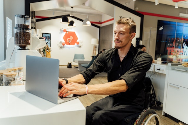 Man in a wheelchair sitting in front of a laptop in an office and working 