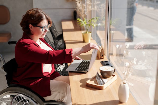 A woman sitting in a wheelchair working on a computer