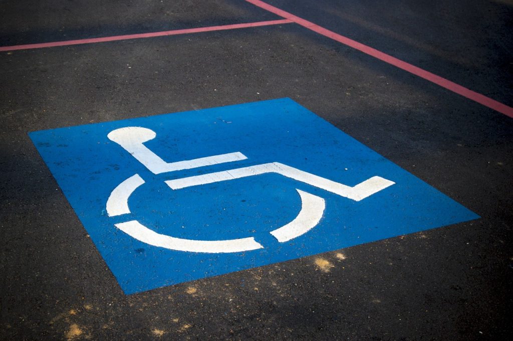 A Blue and White Disability Parking Sign Painted On A Disability Parking Zone Inside Red Line Perimeter. 