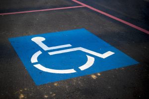 Image Description: A Blue and White Disability Parking Sign Painted On A Disability Parking Zone Inside Red Line Perimeter. Image Credit: https://pixabay.com/photos/handicap-parking-sign-disable-3865315/