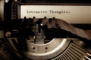 Image Description: Brown & Cream Coloured Image Depicting a Typewriter With Wording "Intrusive Thoughts" Typed On Paper. Image Credit: PhotoFunia.com Category: Vintage Typewriter.