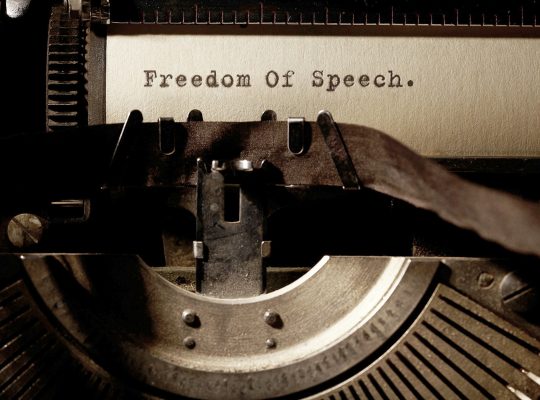 Image Description: Brown & Cream Coloured Image Depicting a Typewriter With Wording "Freedom Of Speech". Typed On Paper. Image Credit: PhotoFunia.com Category: Vintage Typewriter.