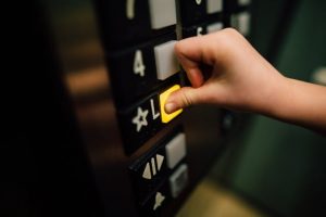 Person pushing a button in an elevator Caption: Moving into a multi-unit building will be easier if accessibility is taken into consideration