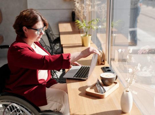 Image Description: A person in a wheelchair working on a laptop. Image Credit: https://www.pexels.com/photo/photo-of-woman-using-laptop-4063619/