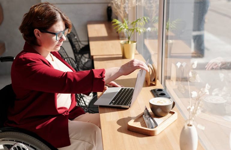 Image Description: A person in a wheelchair working on a laptop. Image Credit: https://www.pexels.com/photo/photo-of-woman-using-laptop-4063619/