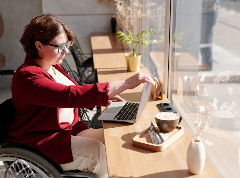 Image Description: A person in a wheelchair working on a laptop. Image Credit: https://www.pexels.com/photo/photo-of-woman-using-laptop-4063619/