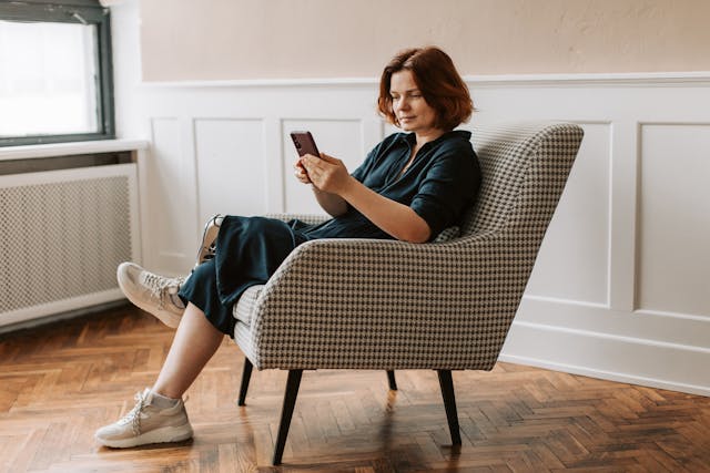 A woman using her phone while sitting by the window