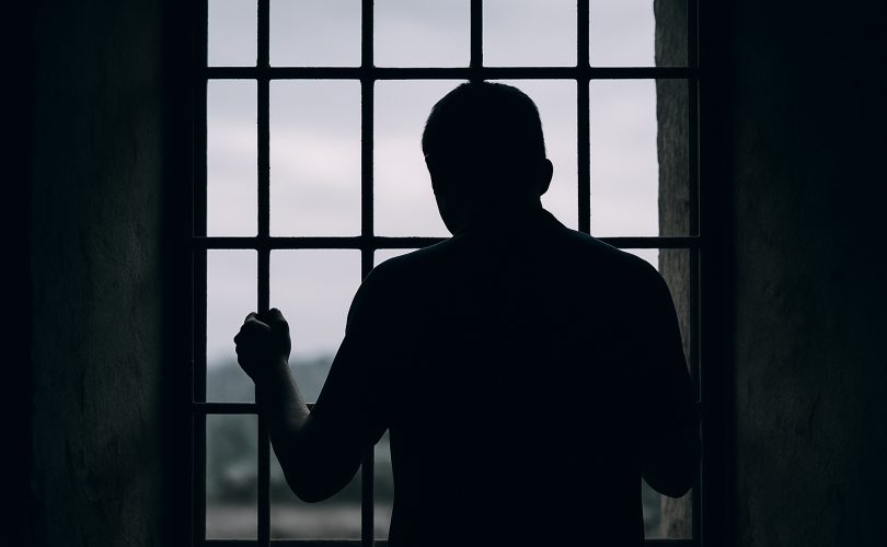 Image credit: © OpenAI / Generated with DALL·E — “Silhouette of a person behind bars symbolising detention and loss of freedom.