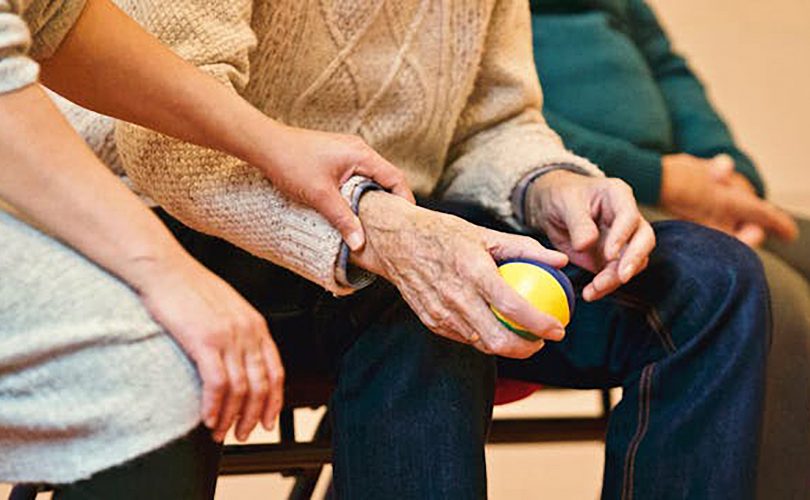 Image Description: An older person sitting next to the caregiver. Image Credit: https://www.pexels.com/photo/person-holding-a-stress-ball-339620/ Matthias Zomer