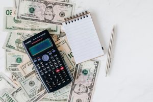 Calculator and Notepad Placed Over Stack Of Paper Bills. Image Credit: Karola G: https://www.pexels.com/@karola-g/ Image Source: https://www.pexels.com/photo/calculator-and-notepad-placed-over-stack-of-paper-bills-4386373/