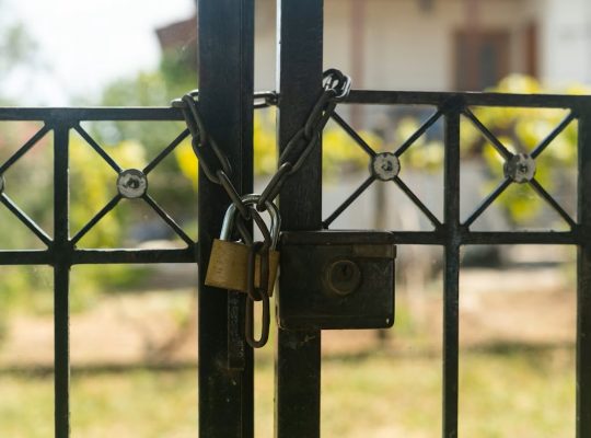 Image Description: Padlock On Gate With A White House In Background. Image Source: https://unsplash.com/photos/a-padlock-on-a-gate-with-a-house-in-the-background-cwkWh_4Fb-M?utm_source=unsplash&utm_medium=referral&utm_content=creditCopyText Image Credit: https://unsplash.com/@avdellidisfotis?utm_source=unsplash&utm_medium=referral&utm_content=creditCopyText