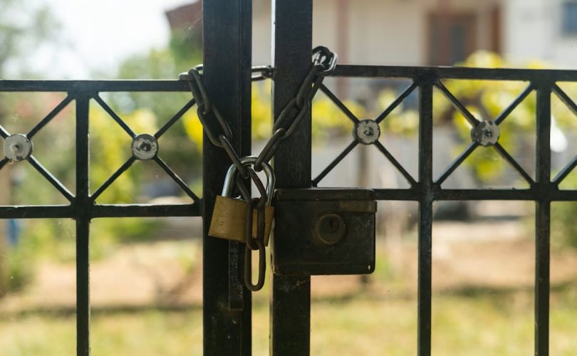 Image Description: Padlock On Gate With A White House In Background. Image Source: https://unsplash.com/photos/a-padlock-on-a-gate-with-a-house-in-the-background-cwkWh_4Fb-M?utm_source=unsplash&utm_medium=referral&utm_content=creditCopyText Image Credit: https://unsplash.com/@avdellidisfotis?utm_source=unsplash&utm_medium=referral&utm_content=creditCopyText