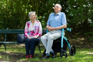 Image Description: Two People sitting in a park, with one person on a bench and the second in a stroller. Image Source: https://www.pexels.com/photo/two-people-sitting-on-a-bench-19971193/ Image Credit: Photo by Rollz International