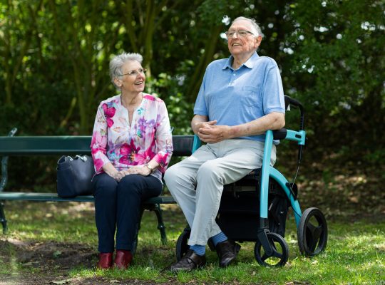 Image Description: Two People sitting in a park, with one person on a bench and the second in a stroller. Image Source: https://www.pexels.com/photo/two-people-sitting-on-a-bench-19971193/ Image Credit: Photo by Rollz International