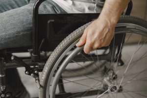 Image Description: A person holding a wheelchair. Image Credit: Gustavo Fring. Image Source: https://www.pexels.com/photo/a-person-holding-a-wheelchair-7446613/