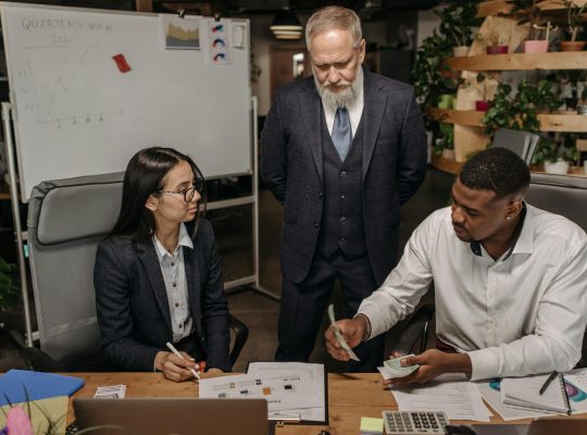 Image Description: A boss looking at a young man and woman sitting at the desk in an office and working. Image Credit: Pavel Danilyuk Image Source: https://www.pexels.com/photo/boss-looking-at-young-man-and-woman-sitting-at-the-desk-in-an-office-and-working-7654424/