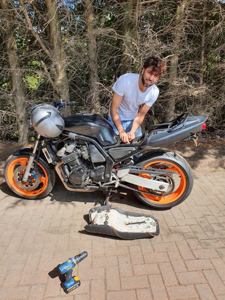 Safir Ahmad doing maintenance to his motorbike, before his accident. Image Credit Safir Ahmad. Copyright 2026